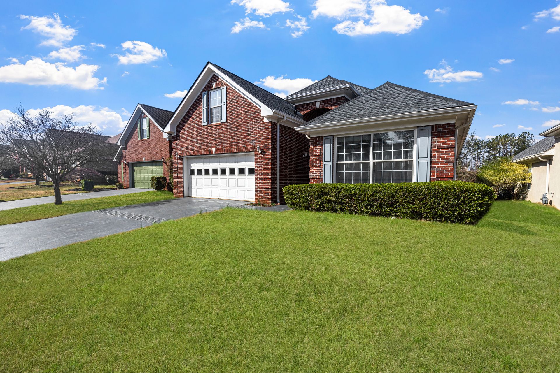 Lovely red brick suburban house with a well-maintained lawn under a bright blue sky.